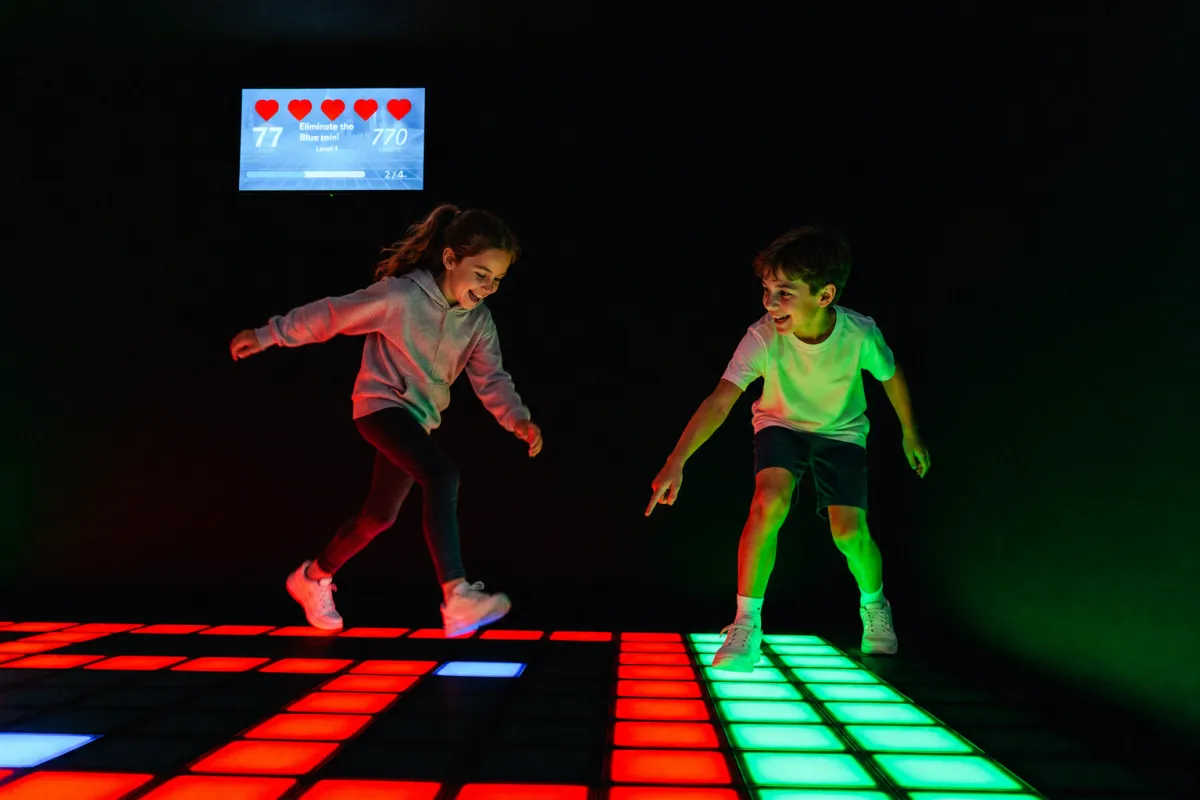 Deux enfants rient en jouant sur la Grille lumineuse de Pixel Rush